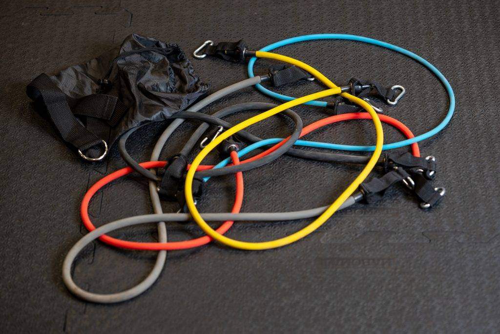 Shopfoto Resistance Bands Einige bunte fitterritter Resistance Bänder liegen auf dem Boden in einem Trainingsraum. Daneben liegt die Aufbewahrungstasche der fitterritter Resistance Bänder.